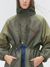 Campera tipo piloto con capucha, cierre frontal con botones y detalle de costuras en zigzag. Presenta cordones ajustables en la cintura y capucha, puños elásticos y logo bordado en el pecho.