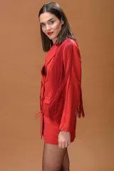 Blazer rojo de corte estructurado con solapas clásicas y cierre de doble botonadura en contraste negro. Presenta flecos largos aplicados en hombros y mangas que aportan movimiento a la prenda.