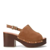 Sandalias de gamuza marrón con plataforma y taco ancho con acabado efecto madera, capellada envolvente abierta en la punta y pulsera ajustable al tobillo con hebilla metálica. Cuenta con detalles de tachas metálicas doradas a lo largo de la plataforma.