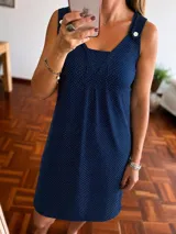 Camisón corto sin mangas de color azul marino con estampado de lunares blancos. Presenta un escote cuadrado con detalle de dos botones decorativos en los hombros y pliegues frontales en el pecho.