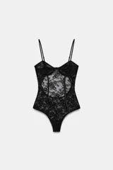 Body de encaje negro con diseño de corsetería, escote en pico y tirantes finos ajustables. Presenta paneles de encaje floral con transparencias y costuras estructuradas.