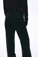 Jean de denim de algodón con leve stretch, de tiro alto y corte wide leg. Presenta cierre frontal con doble botón, bolsillos traseros de parche y pliegues marcados en la parte delantera y trasera.