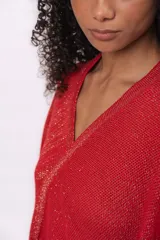 Ruana tejida de punto en algodón con destellos de lurex, de corte asimétrico y escote en V. Presenta una etiqueta de cuero con el logo de la marca en el frente.