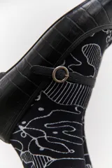 Ballerinas color borgoña con estampado croco, punta redondeada y tira sobre el empeine con hebilla metálica.