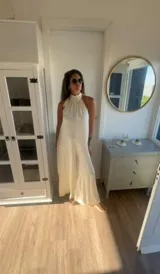 Mono largo de satén color blanco, con cuello halter y diseño amplio de pierna ancha.