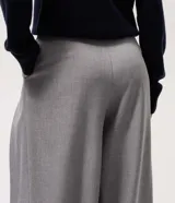 Pantalón de sastrería modelo pantalona, de corte amplio y tiro alto. Presenta pinzas frontales, cierre con cremallera y botón, y presillas en la cintura. Incluye un cinturón ajustable del mismo tejido.