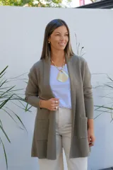 Saco tipo cárdigan abierto de punto fino en color verde oliva, con mangas largas y bolsillos frontales aplicados.