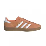 Championes adidas modelo Gazelle, confeccionados en gamuza color naranja con las icónicas tres tiras laterales en blanco. Presentan suela de goma color caramelo y detalle de talón en blanco.