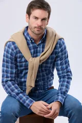 Camisa de manga larga con estampado de cuadros en tonos azules, cuello abotonado y cierre frontal con botones.