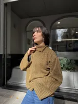 Polera de punto color ocre con diseño acanalado, cuello alto con abertura lateral y mangas amplias de corte recto.