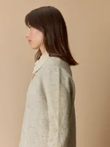 Buzo de lana con escote en V, diseño de rombos y detalles en hilo metalizado. Presenta mangas largas y corte holgado.