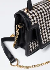 Cartera de mano con estampado pata de gallo en blanco y negro, detalles en cuero sintético negro y correa de cadena dorada.