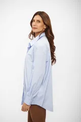 Camisa de corte oversize con cuello clásico, cierre frontal de botones y mangas largas con puños abotonados.