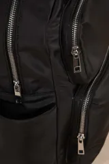 Mochila color verde militar de nylon con asa fija doble, dos bolsillos externos frontales con cierre, dos compartimentos laterales y un compartimento interno grande.