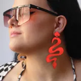 Par de aros colgantes con forma de serpiente, color rojo metalizado.