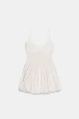 Vestido mini de escote redondo y tirantes finos en color beige con estampado de cuadros vichy. Presenta detalle de tejido tipo nido de abeja en el torso y bajo acabado tipo globo.