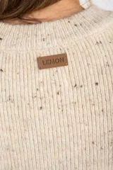 Chaleco de punto sin mangas en color beige melange con motas oscuras. Presenta cuello redondo y terminaciones acanaladas en el ruedo y las sisas.