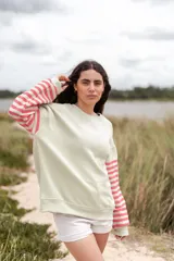 Buzo color verde claro con mangas largas a rayas horizontales rosas y blancas.