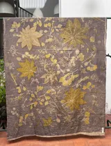 Mantel rectangular de algodón color gris con estampado de hojas y flores en tonos amarillos y marrones.