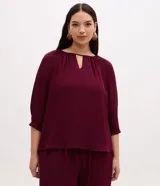 Blusa de crepé bordó con mangas 3/4, escote redondo con abertura en V y detalles fruncidos en el cuello.