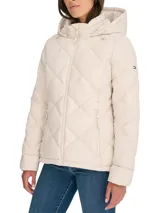 Campera acolchada color crema, con capucha, cierre de cremallera frontal, bolsillos laterales y logo de Tommy Hilfiger en la manga izquierda.