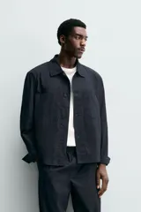 Sobrecamisa regular fit confeccionada en popelín de algodón color negro, con cuello solapa, bolsillos de plastrón en el pecho y cierre frontal con botones.