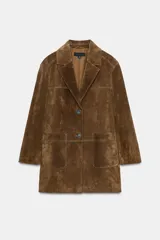 Chaqueta larga de piel color marrón, con cuello solapa, manga larga, bolsillos delanteros de plastrón y cierre frontal con botones.