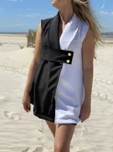 Chaleco corto sin mangas, con solapas y diseño color block en blanco y negro. Presenta un cinturón ancho con hebilla dorada.