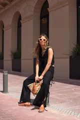 Pantalón negro de tejido ligero, corte holgado, cintura elastizada y aberturas laterales con lazos.