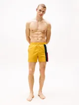 Short de baño amarillo con cintura elástica ajustable con cordón. Presenta una banda vertical en el lateral con los colores blanco, azul marino y rojo.