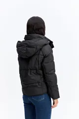 Campera puffer negra con capucha, diseño corto y acolchado, cierre frontal con botones a presión y puños ajustados.