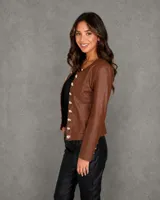 Chaqueta de cuero sintético color marrón, con cuello redondo y cierre frontal de doble botonadura metálica plateada.