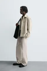 Sobrecamisa de hombre con corte relajado, confeccionada en tejido texturizado jaspeado en tonos beige y negro. Presenta cuello solapa, manga larga con puño de botón y cierre frontal de botonadura.