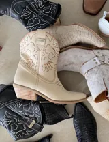 Bota corta estilo western de cuero color marrón, con taco cuadrado de 5 cm y diseño clásico. Presenta un acabado desgastado en la puntera y el talón.