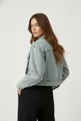 Campera de jean celeste de manga larga, con cuello camisero, botones frontales y bolsillos de parche con solapa en el pecho.