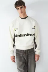 Buzo de cuello redondo con calce relajado, confeccionado en fleece. Presenta un diseño en color blanco con paneles laterales en contraste color gris oscuro, y estampados gráficos frontales con la palabra Unlimited.