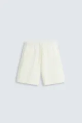 Bermuda de algodón color blanco roto, de corte relajado (relaxed fit), con cintura elástica ajustable mediante cordón y bolsillos laterales y trasero de plastrón.