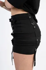 Minifalda negra con tres hileras de correas ajustables con hebillas plateadas.