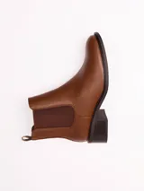 Bota tipo Chelsea color marrón, con paneles laterales elásticos, punta redondeada y taco cuadrado bajo.
