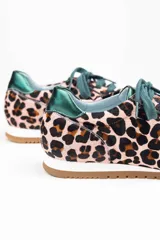 Zapatillas de estilo running con estampado animal print de leopardo sobre fondo rosado. Presentan detalles en color verde botella en la lengüeta, cordones, collarín y talón. Cuentan con suela de goma dentada y cuña interna oculta para mayor comodidad.