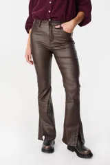 Pantalón de tiro medio con acabado engomado en color marrón oscuro. Presenta un corte recto con aberturas laterales en el ruedo, cierre frontal con botón y bolsillos funcionales.