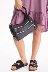 Cartera tipo morral de poliuretano símil cuero, color negro, con diseño rectangular, múltiples bolsillos frontales con cierres metálicos y correa de hombro ajustable.