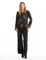 Camisa de crepe con estampado floral en tonos verdes y marrones, cuello con solapa, cierre frontal con botones y detalle de mostacillas bordadas en los hombros. Presenta mangas largas con terminación amplia.