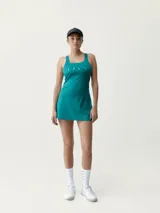 Vestido deportivo turquesa con sujetador integrado y copas extraíbles, confeccionado en tejido Shapplex_B, compacto y ligero. Cuenta con puntos reflectantes en la espalda y diseño de corte evasé con short interno.