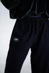Pantalón de jogging negro de corte holgado, con cintura elástica ajustable mediante cordón y logo pequeño estampado en la pierna derecha.