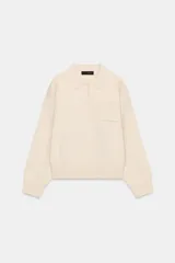 Jersey de punto color beige, con cuello polo, manga larga con puños y cierre frontal con botones. Presenta un bolsillo de plastrón en el pecho.