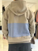 Hoodie de felpa con capucha y medio cierre frontal, diseño en bloques de color celeste y blanco, con bordados decorativos en el pecho.