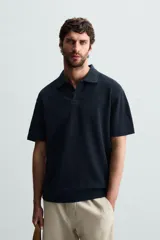 Polo de manga corta color azul marino con tejido de punto jacquard, cuello solapa y cierre frontal de dos botones. Cuenta con acabado en rib en el cuello, mangas y ruedo.
