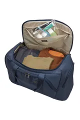 Bolso tipo duffel de la marca Thule, color azul oscuro, con diseño estructurado y compartimentos múltiples. Cuenta con asas reforzadas, correa de hombro ajustable y desmontable, cierre principal con doble cremallera y bolsillos laterales y frontales organizadores.