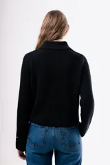 Cardigan de punto acanalado color negro, con cuello camisero, cierre frontal de botones y dos bolsillos delanteros aplicados.